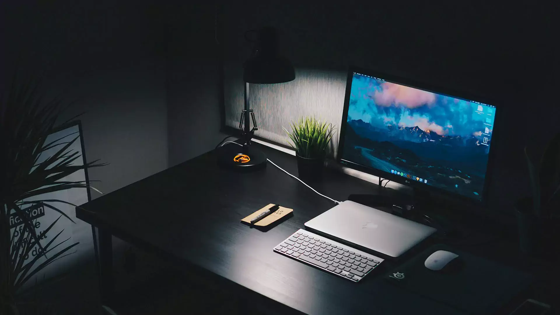 A variety of black desk accessories, including a monitor stand, desk lamp, cable organizer, and plant, to enhance your workspace and complement your Space Black MacBook Pro.